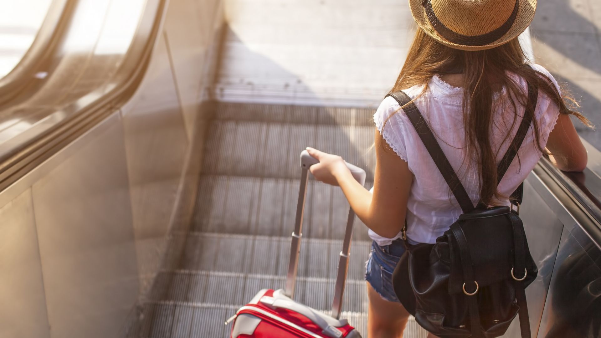 Young woman with suitcase on escalator